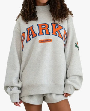 A light gray crewneck sweatshirt featuring 'PARKE' in red varsity-style block letters with black outlines across the chest, and a small red 'ALABAMA' logo underneath. A small 'P' logo is visible on the left sleeve cuff.