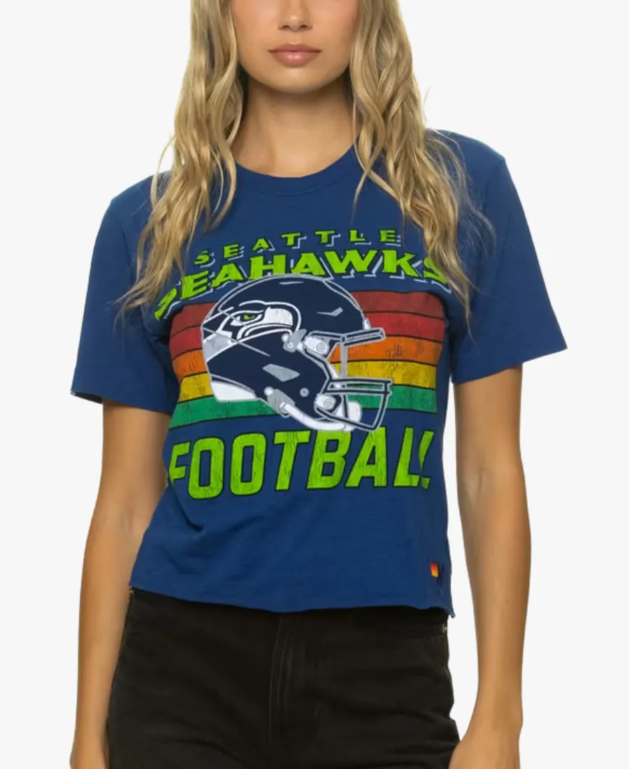 A woman wearing a blue Seattle Seahawks football graphic t-shirt with a rainbow stripe design and a helmet graphic on the front, paired with black pants.