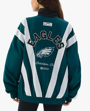 A woman shown from the back wearing a Philadelphia Eagles themed jacket. The jacket features dark teal green and white diagonal stripes with 'EAGLES' and the team logo printed on the back.