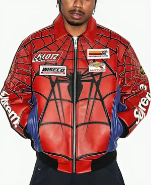 A man wearing a Spider-Man themed leather jacket with red, blue, and black web patterns, featuring sponsor patches including Klutz, Wiseco, and K&N.